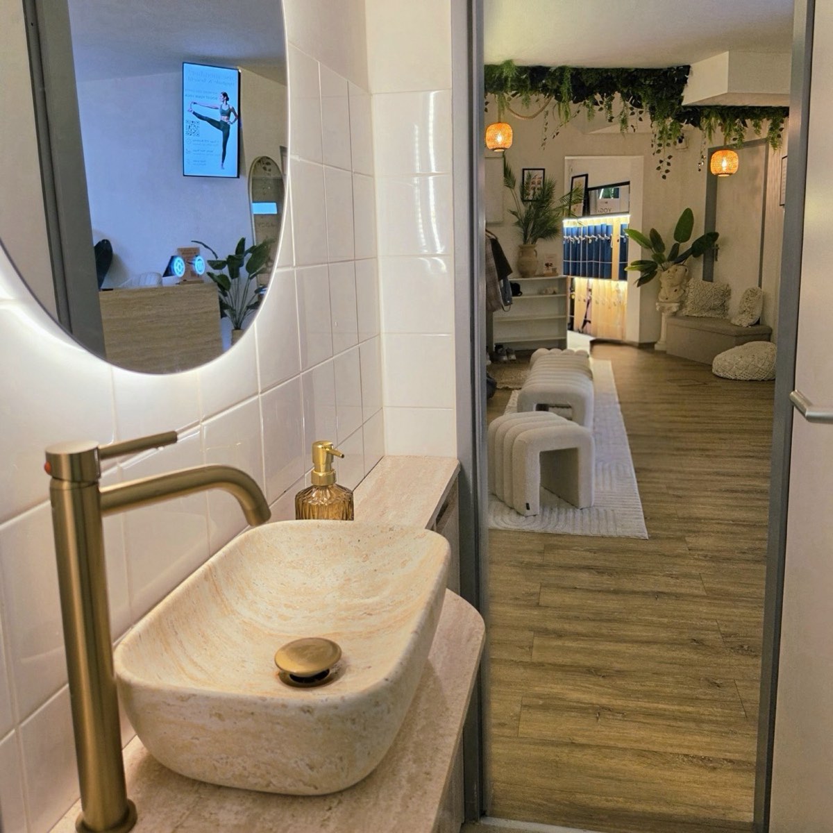 Bad mit Steinwaschbecken, beleuchtetem Spiegel und Blick in die Garderobe